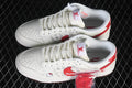 Pair of cream and red low-top sneakers with patterned side panels, character graphics, and a spare red lace.