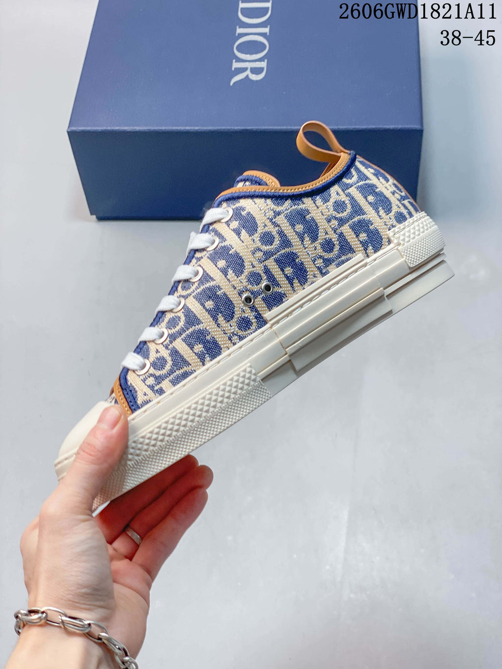 Side view of a blue and beige patterned low-top sneaker with cream-colored sole and tan trim
