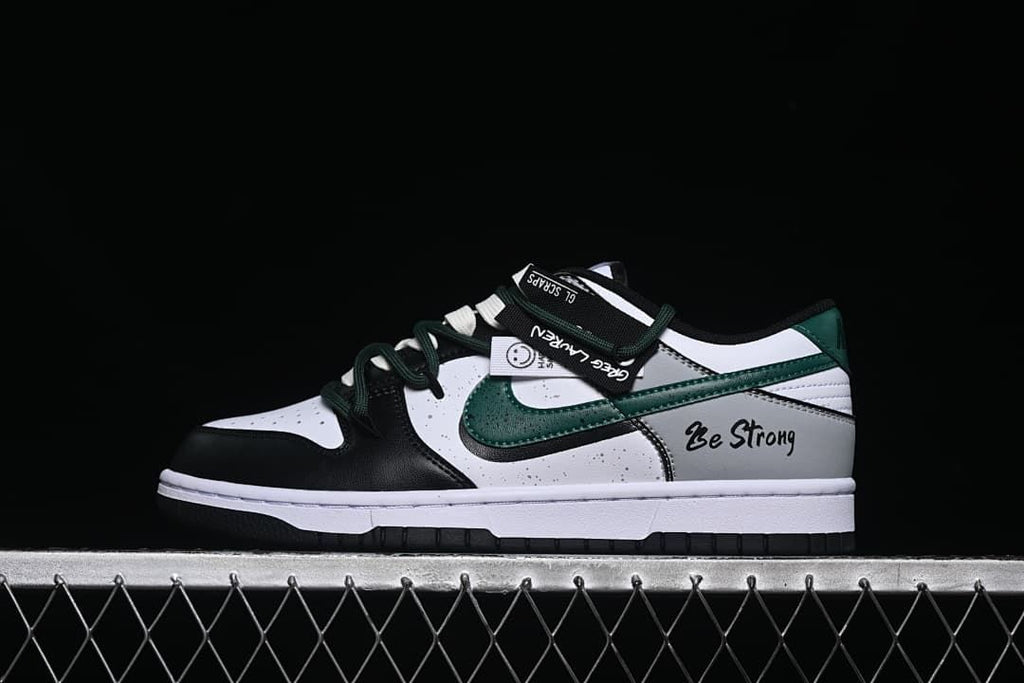 Side view of the sneaker with strap detail and Be Strong lettering