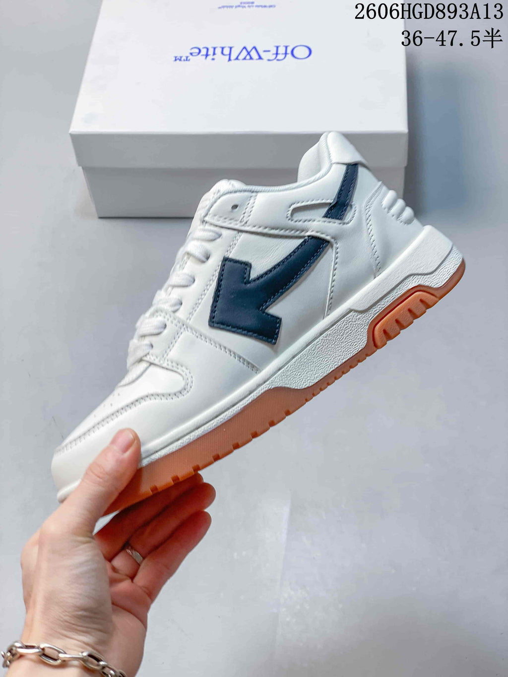 Side view of the white sneakers with black side detailing and gum-colored outsole.