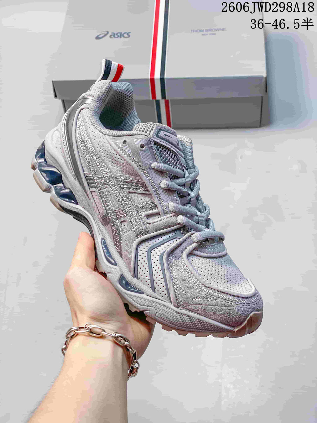 Angled side view of the silver-toned sneaker with layered panels and heel pull tab.
