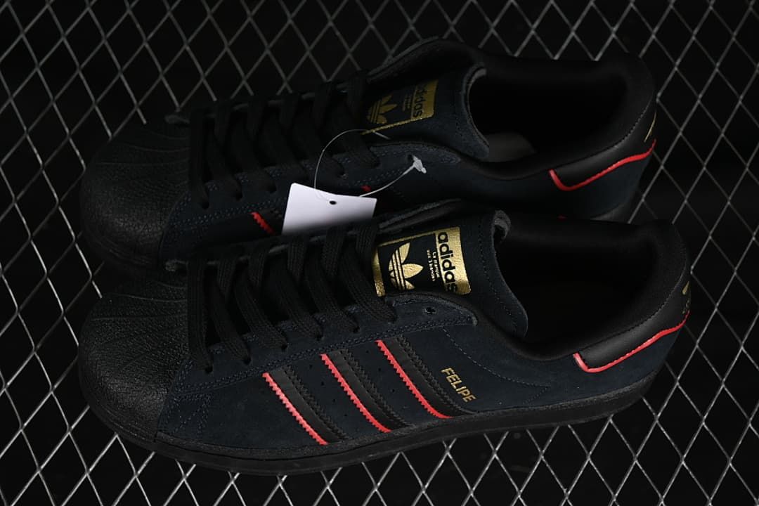Pair of black low-top sneakers with red accents and gold-tone details