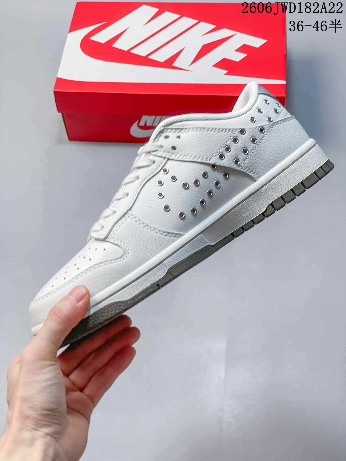 Side view of a white low-top sneaker with silver-tone studs and a gray outsole