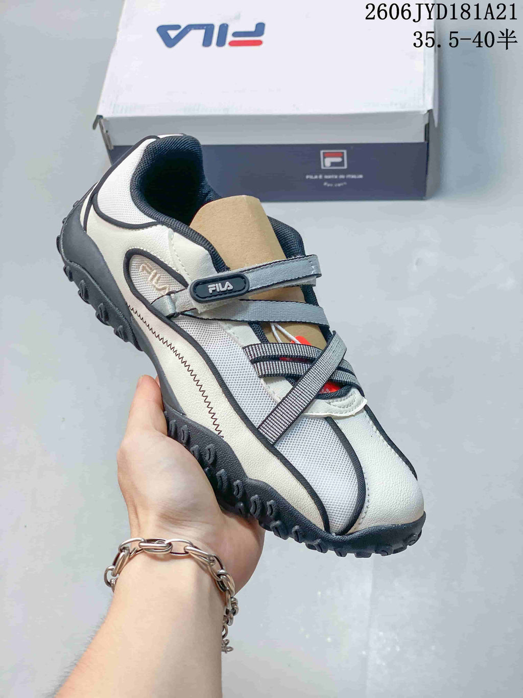 Angled front and side view of a white and gray FILA Pebble sandal-style shoe.