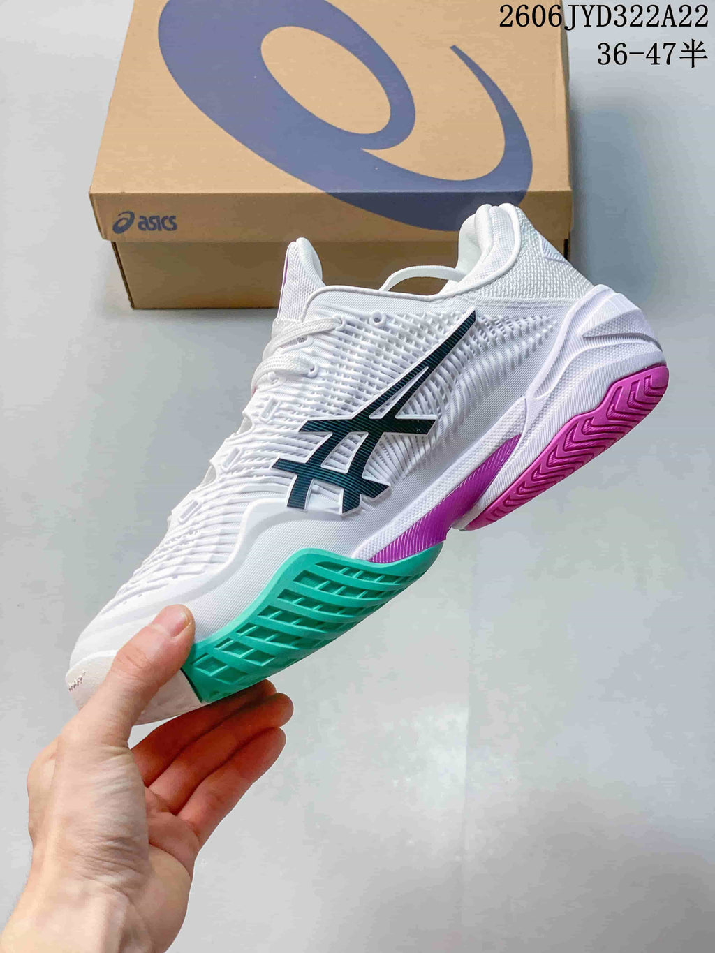 Side view of a white ASICS tennis shoe with dark side branding and teal and magenta outsole accents.