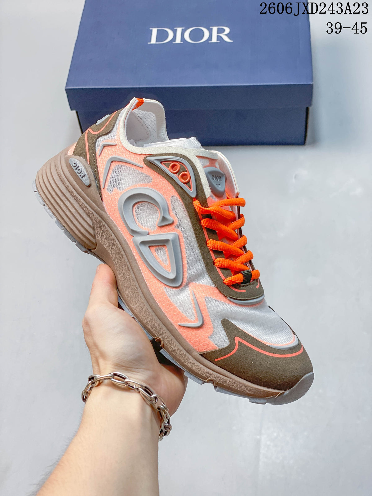 Light gray low-top sneaker with coral accents and bright orange laces.