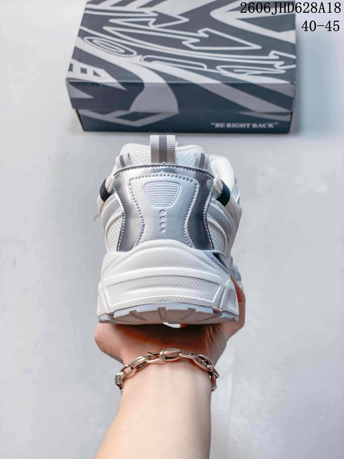 Rear view of the white and silver sneaker showing the heel and pull tab