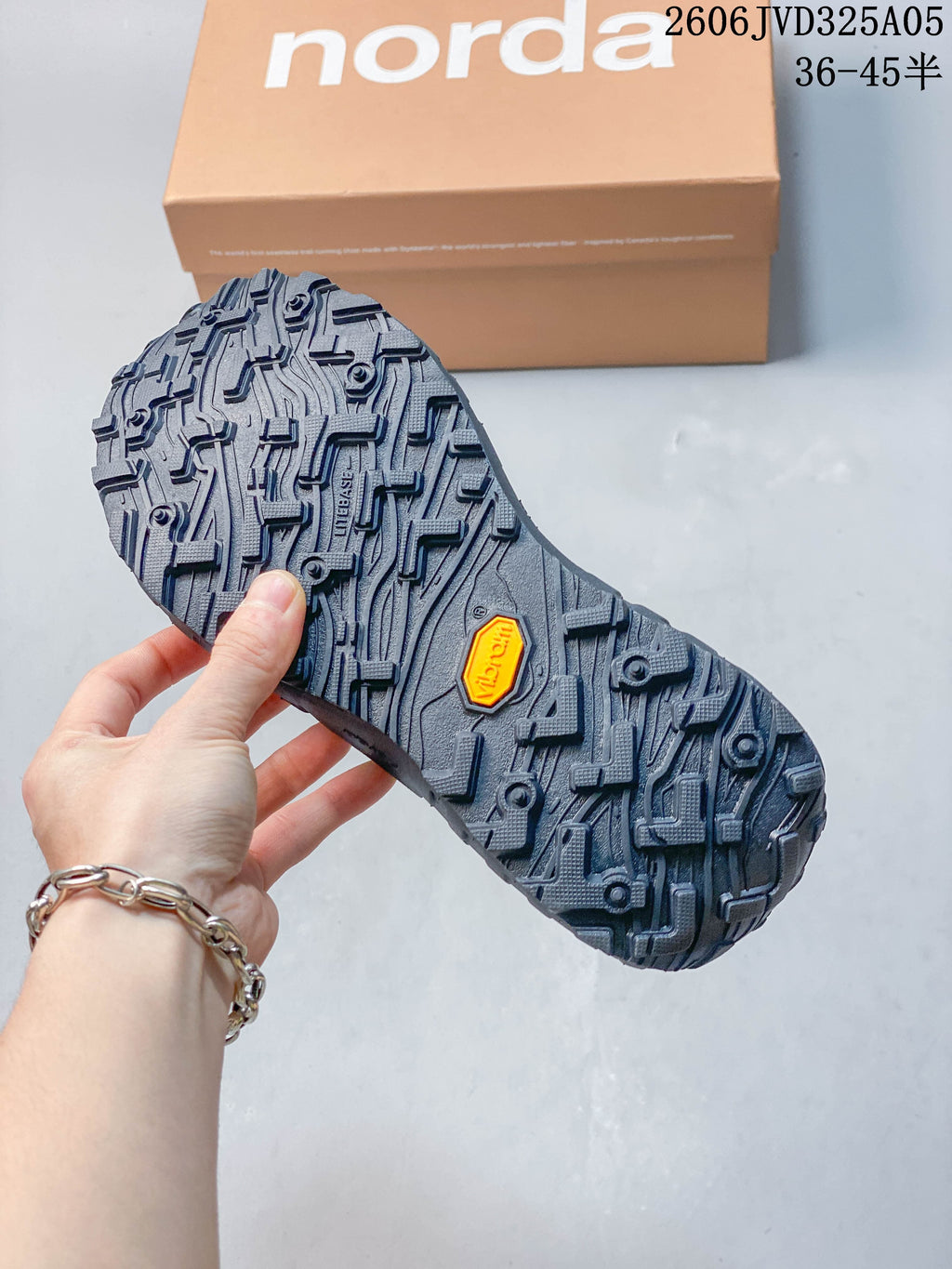 Close-up of the shoe’s patterned dark outsole and branded box.