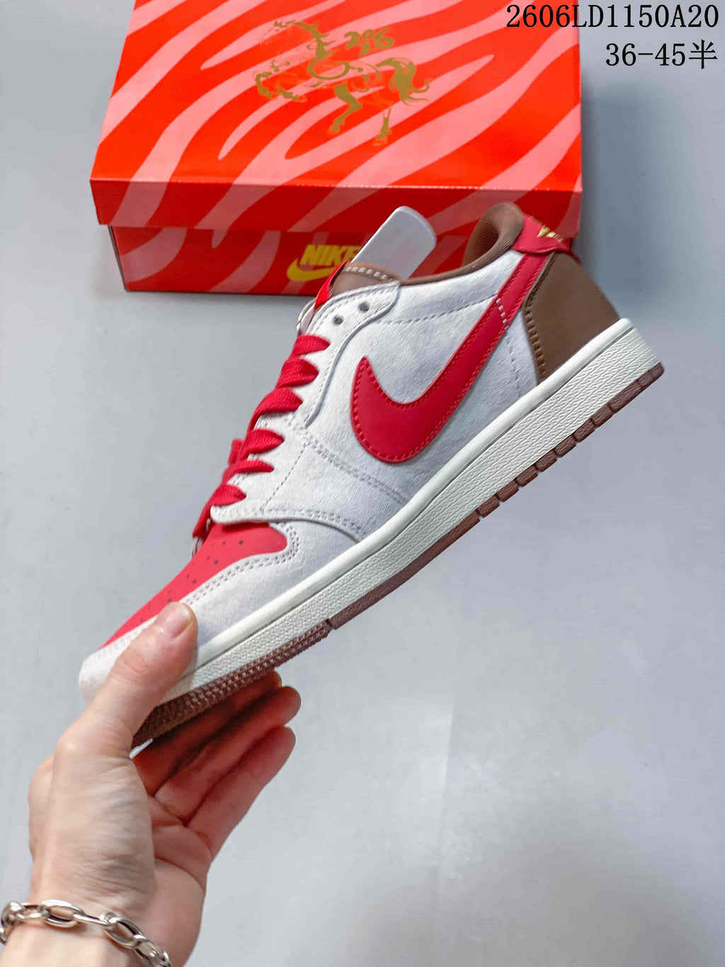 Side view of the sneaker with a red Swoosh, light grey panels, and brown heel.