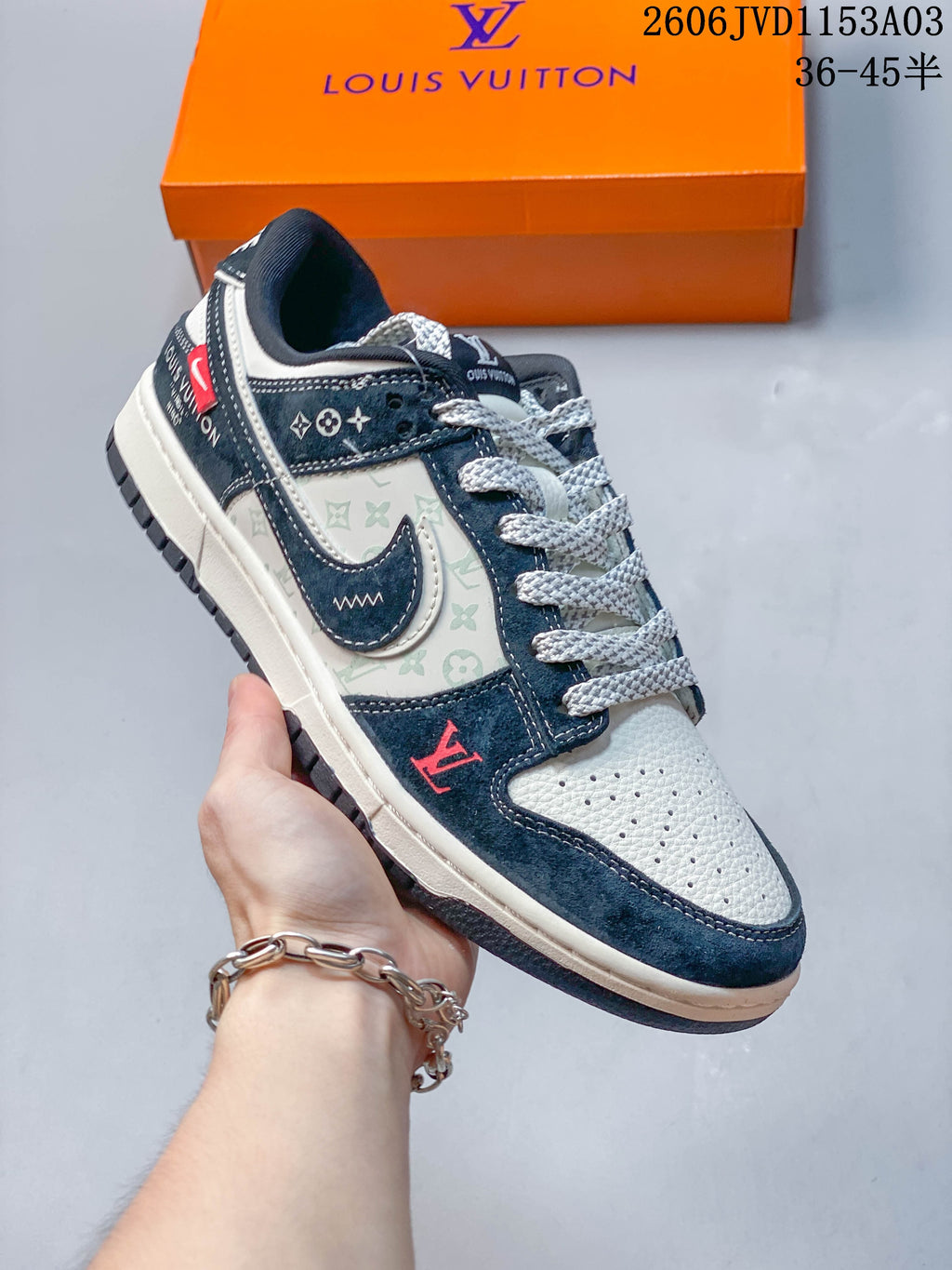 Navy and light gray low-top sneaker viewed from the side, showing patterned panels and layered swoosh-shaped detail