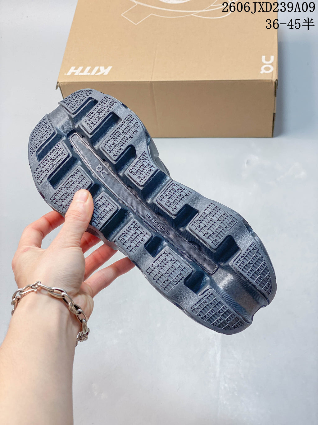 Underside of a charcoal shoe showing segmented tread and a central sole channel.