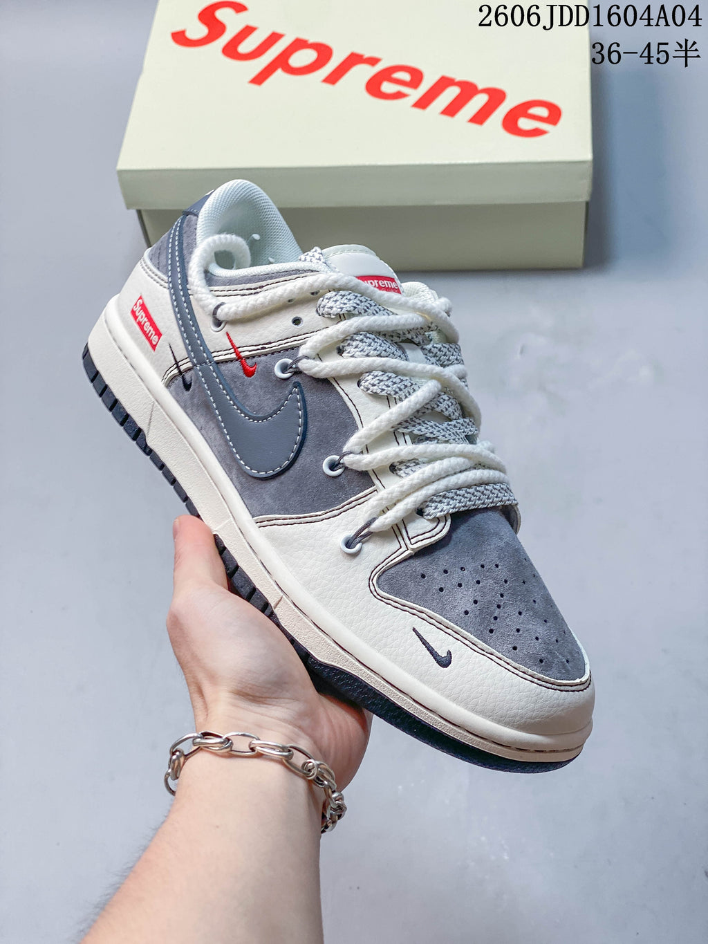 Angled view of the gray and white Nike SB Dunk Low sneaker with red accents