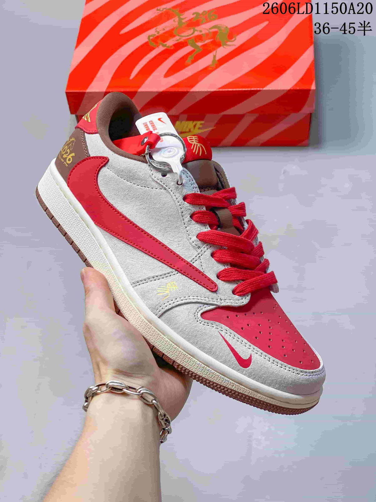 Close view of a gray and red sneaker with a red side stripe, red toe panel, and brown heel accents.