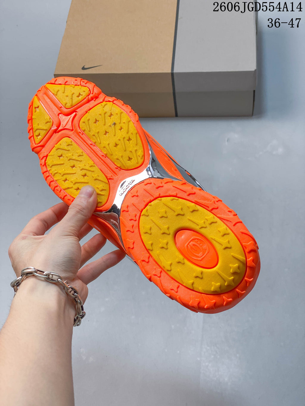 Underside of the orange sneaker showing a patterned yellow-and-orange outsole