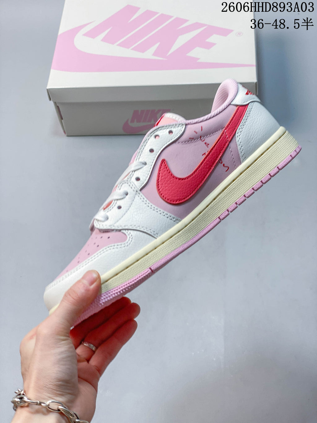 Side profile of a pink and white low-top sneaker with a red Swoosh and cream midsole; image overlay states a size range.