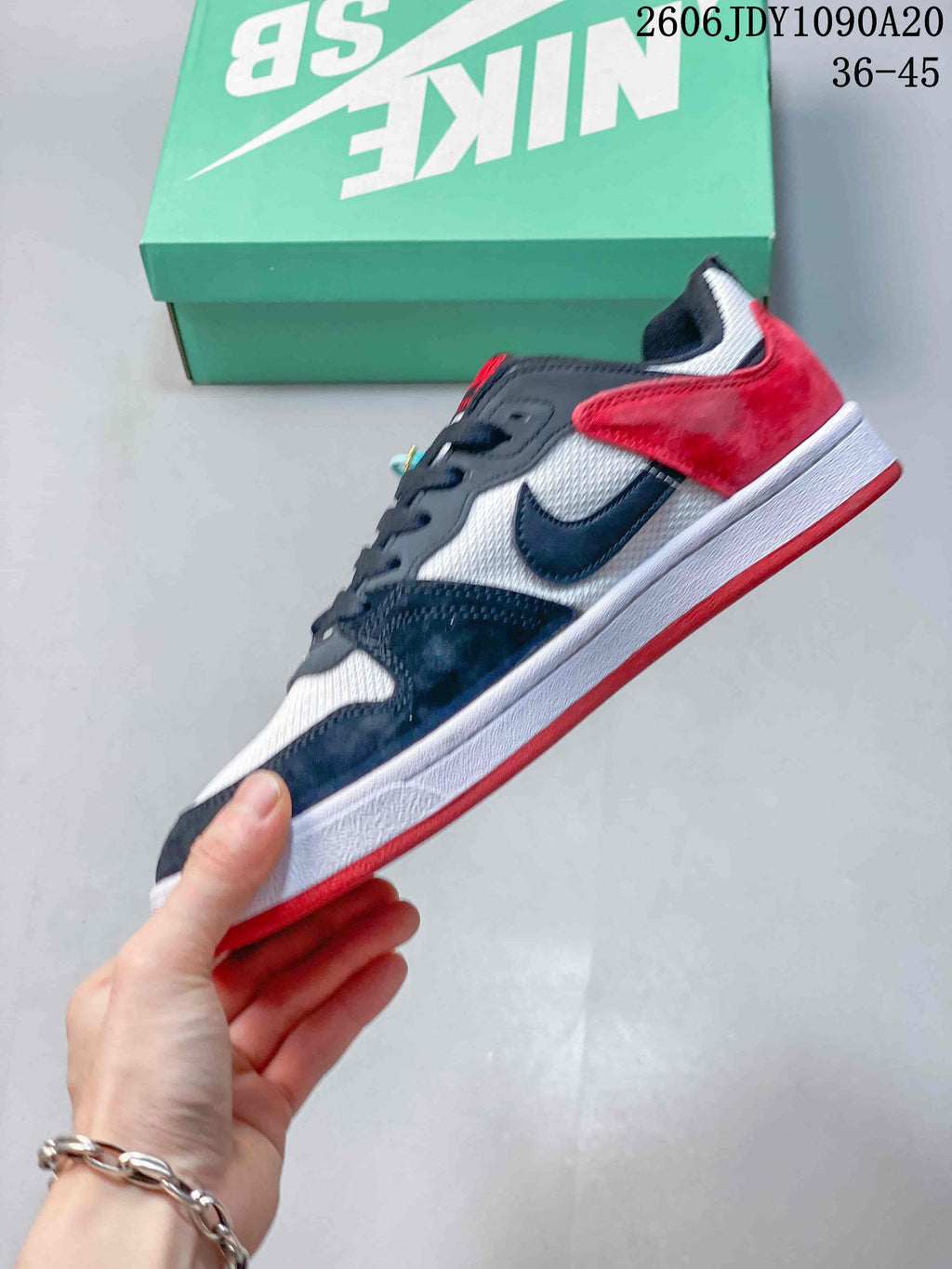 Side view of a Nike SB Alleyoop sneaker with dark overlays, a white upper, and red heel panel