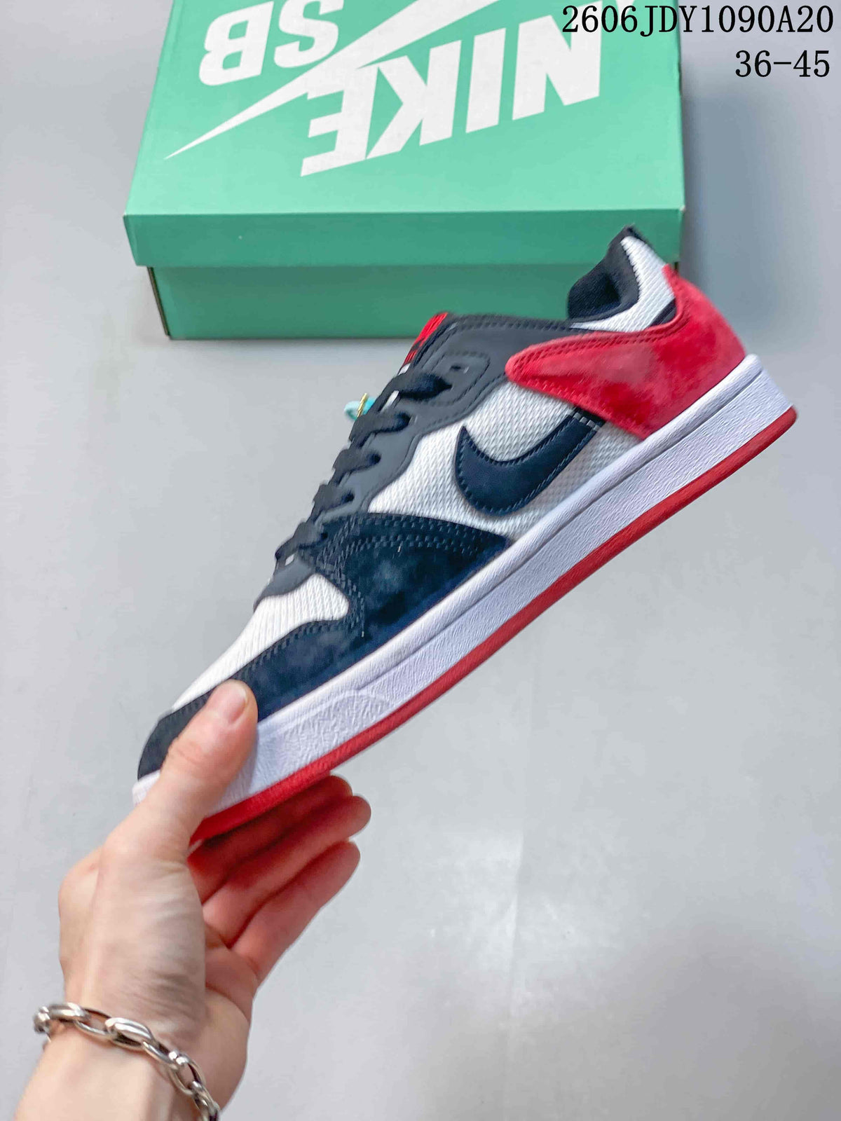 Side view of a Nike SB Alleyoop sneaker with dark overlays, a white upper, and red heel panel