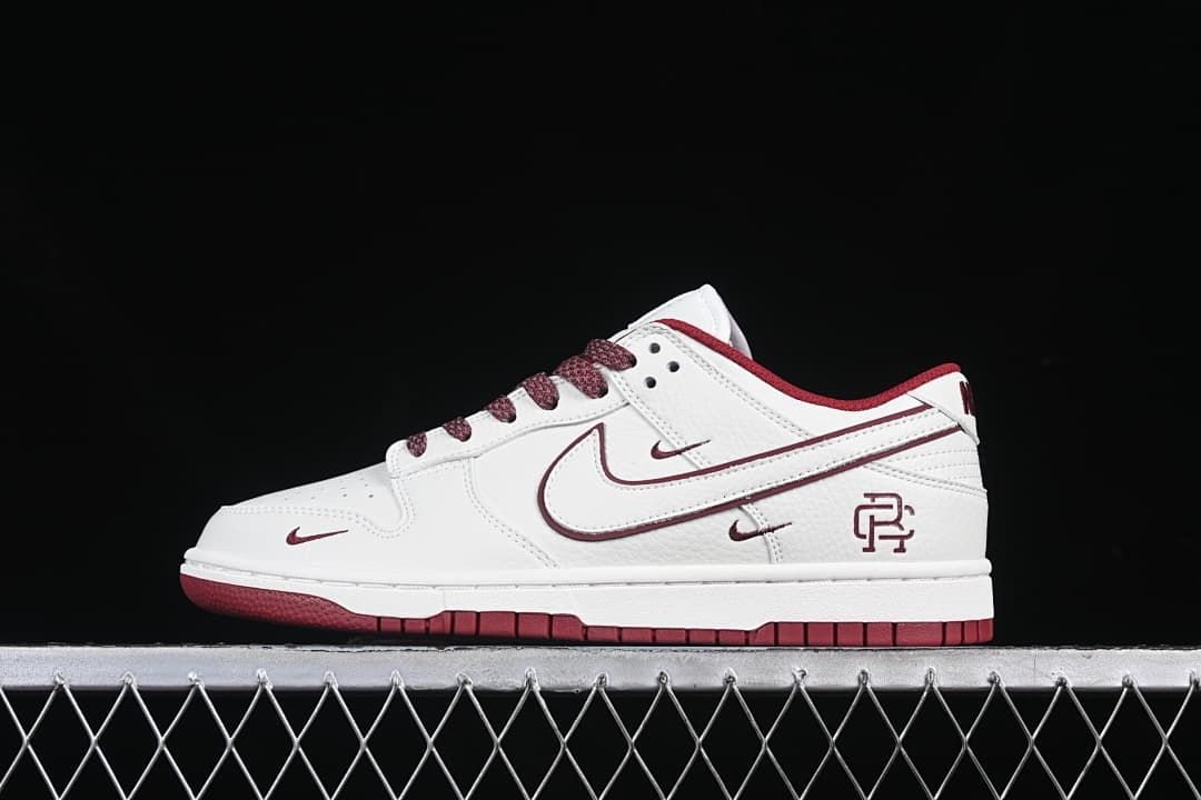 Side view of a white and burgundy Reigning Champ Nike SB Dunk Low sneaker