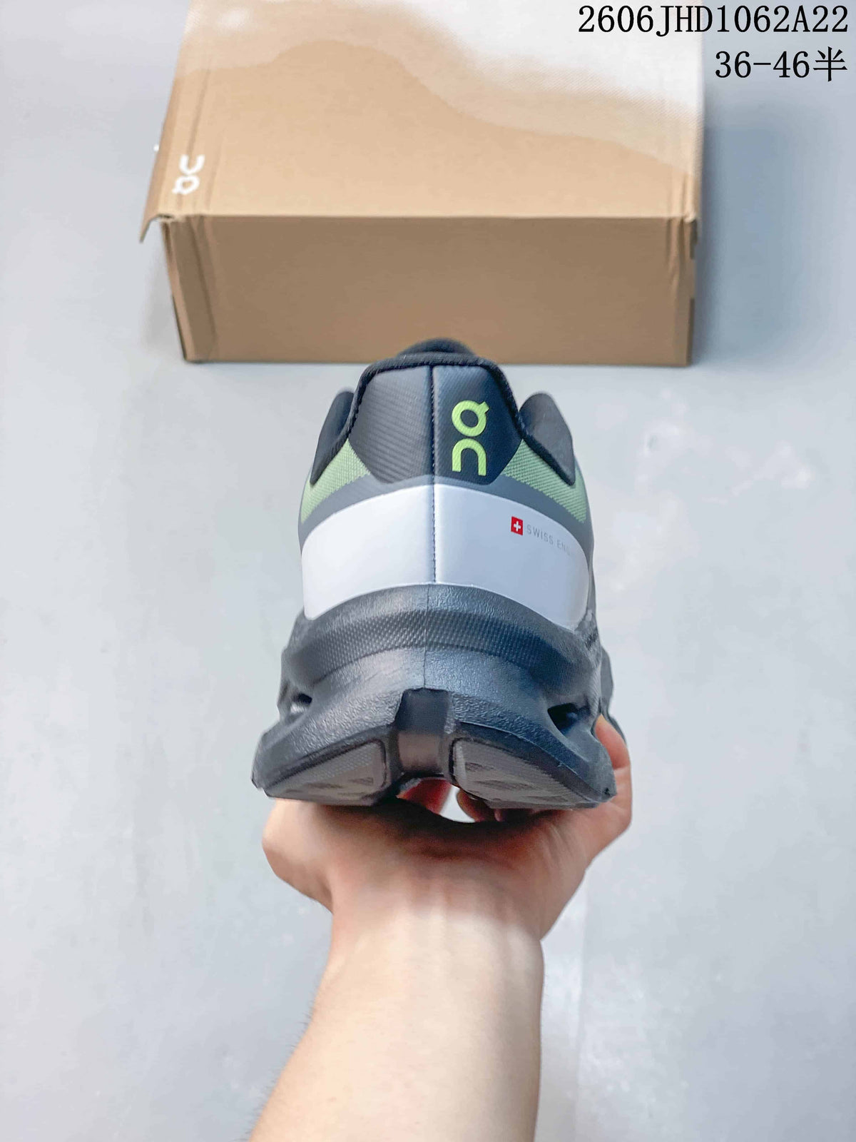 Rear view showing the heel and sculpted sole of a gray and lime On sneaker.