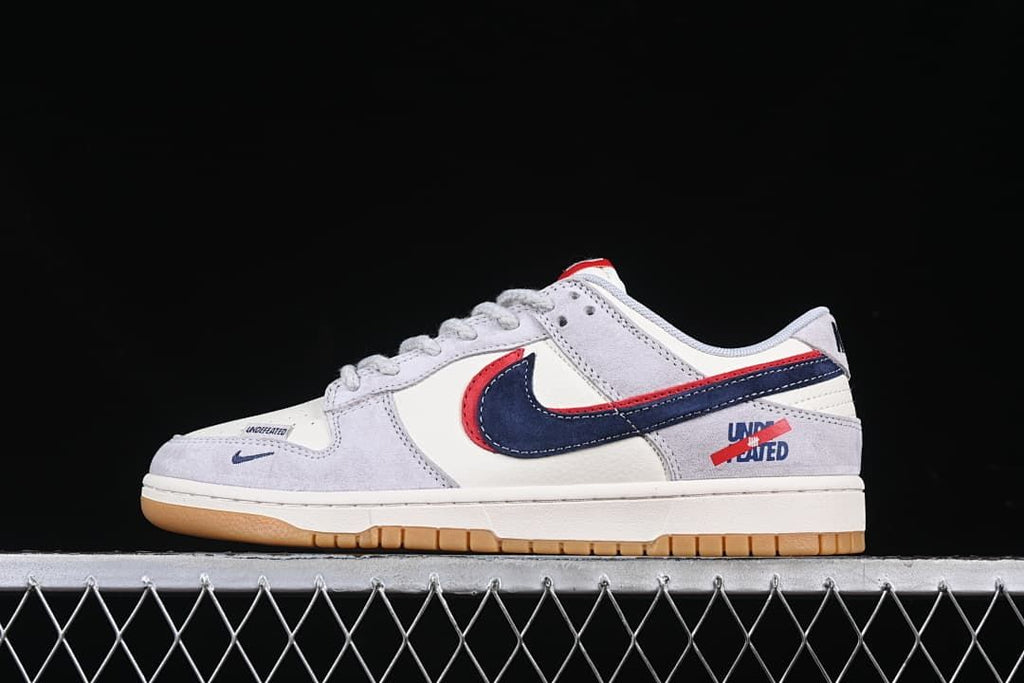 Side profile of the Nike SB Dunk Low in off-white, grey, navy, red and gum colors.