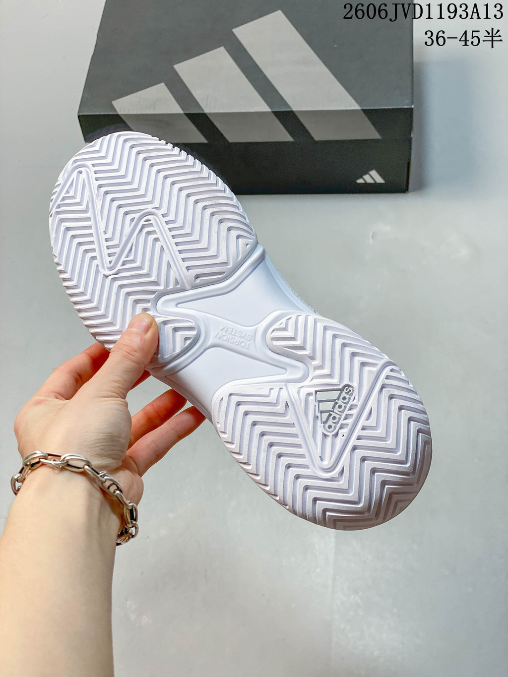 Close-up of the patterned outsole on a white Adidas tennis shoe