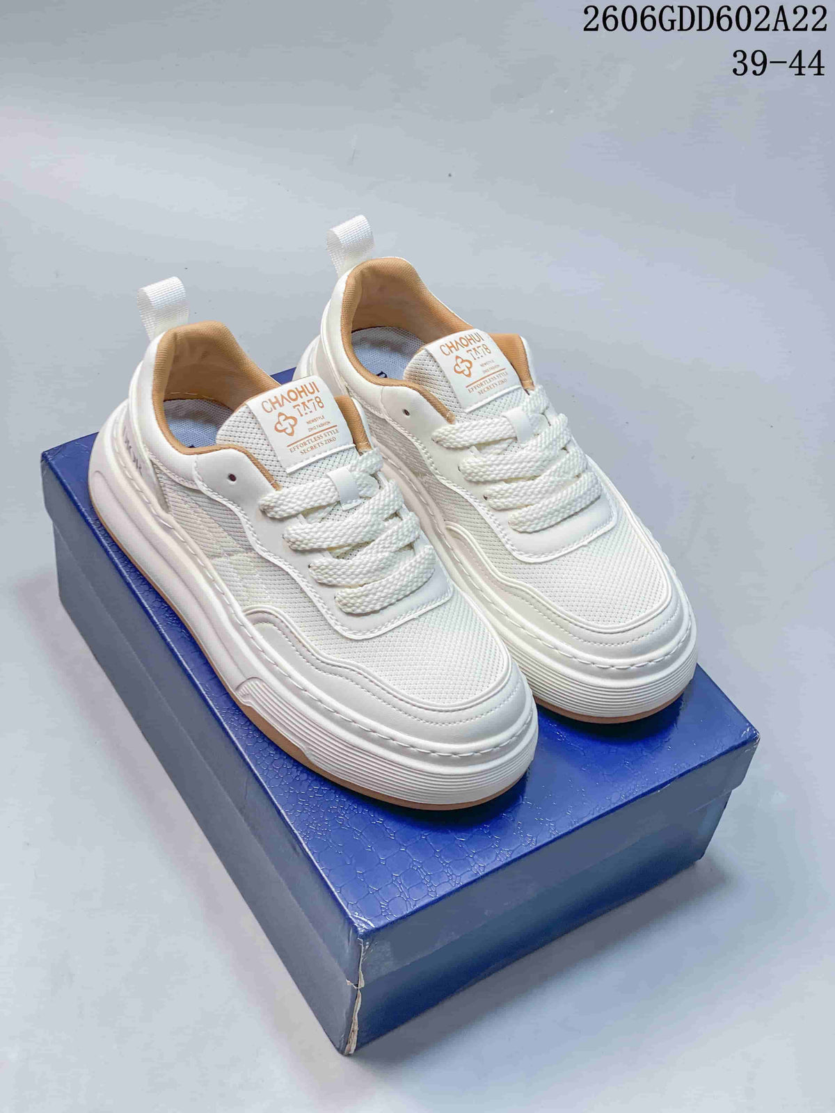 White low-top lace-up sneakers with layered panels and thick soles, photographed as a pair.