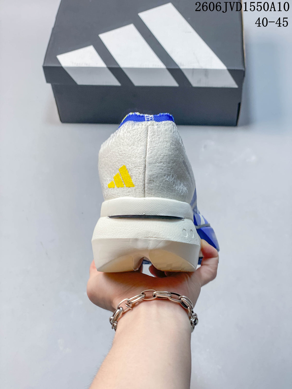 Rear view of a white running shoe with a yellow Adidas mark and sculpted sole.