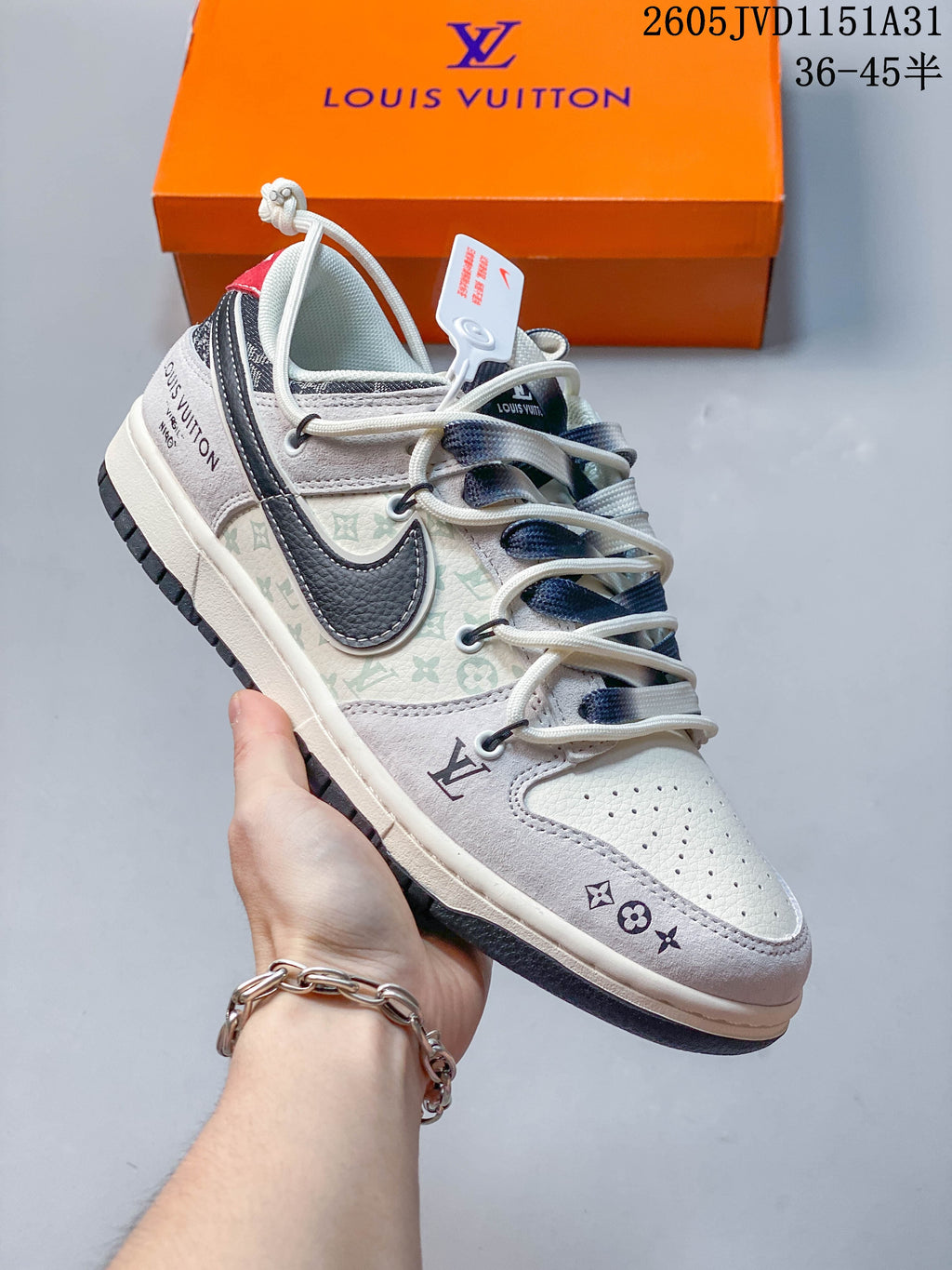 Close view of a cream and gray low-top sneaker with patterned panels, layered laces, and a dark swoosh-shaped overlay.