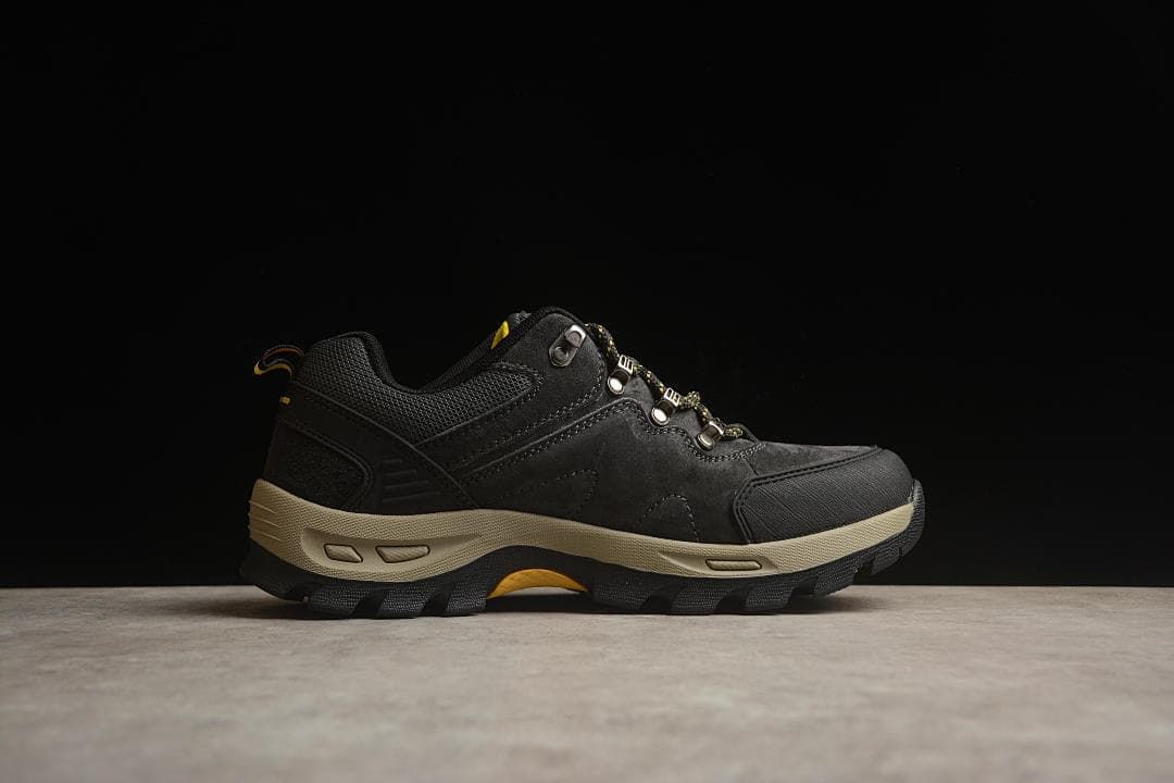 Side profile of the black hiking shoe with beige midsole and yellow outsole accents.