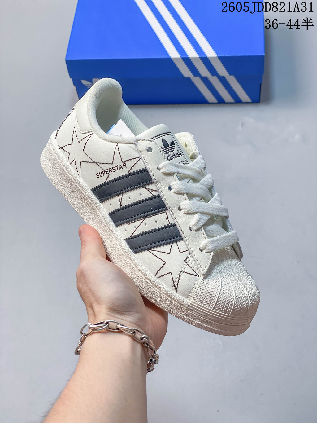 Close-up of a white Adidas Superstar with dark side stripes, star graphics and a shell-shaped toe.