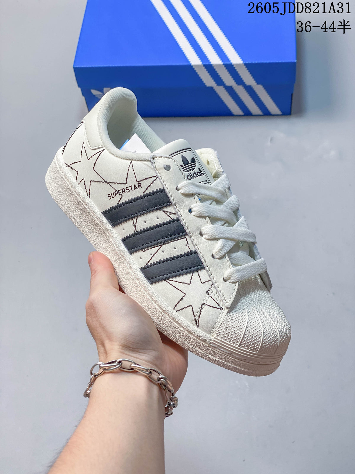 Close-up of a white Adidas Superstar with dark side stripes, star graphics and a shell-shaped toe.