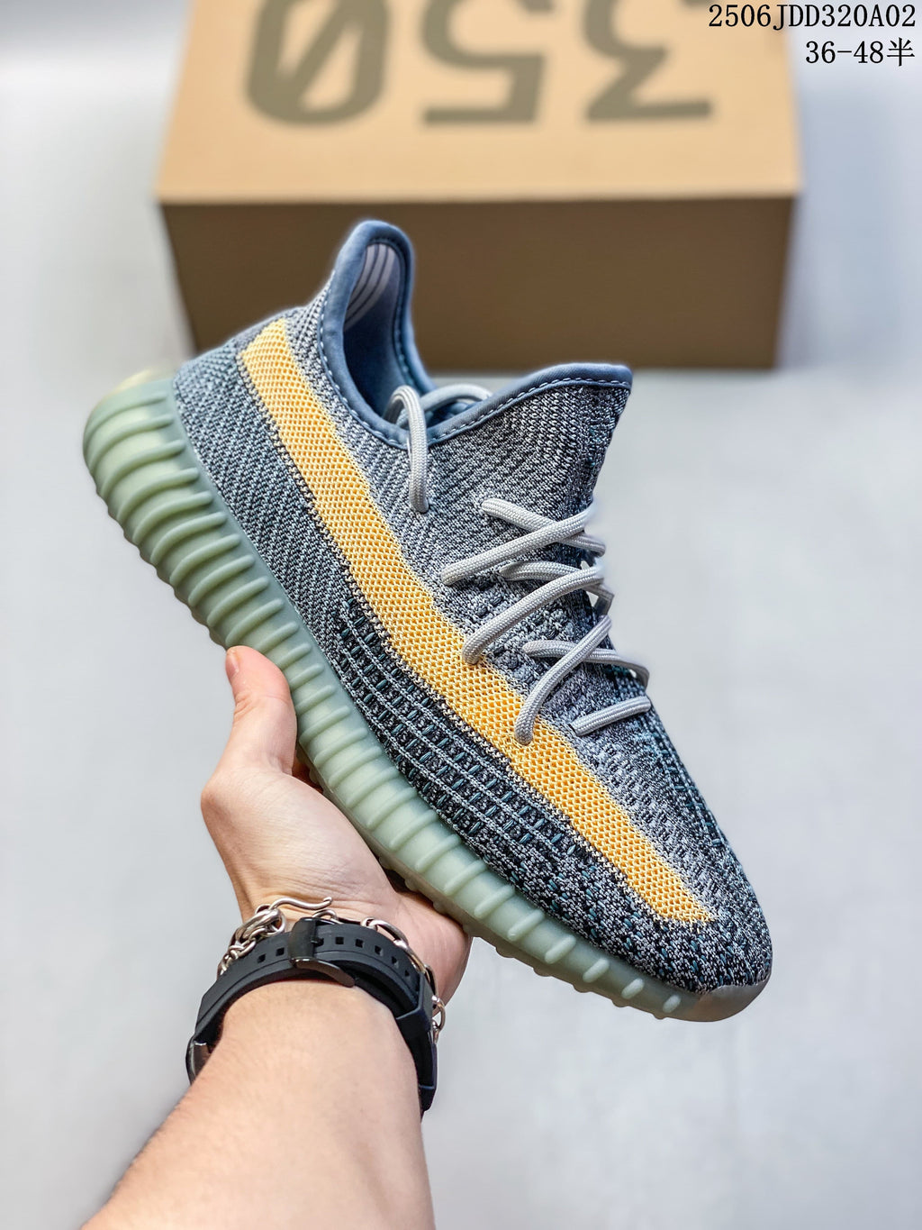 Gray Adidas Yeezy-style sneaker with a yellow side stripe and green-tinted sole