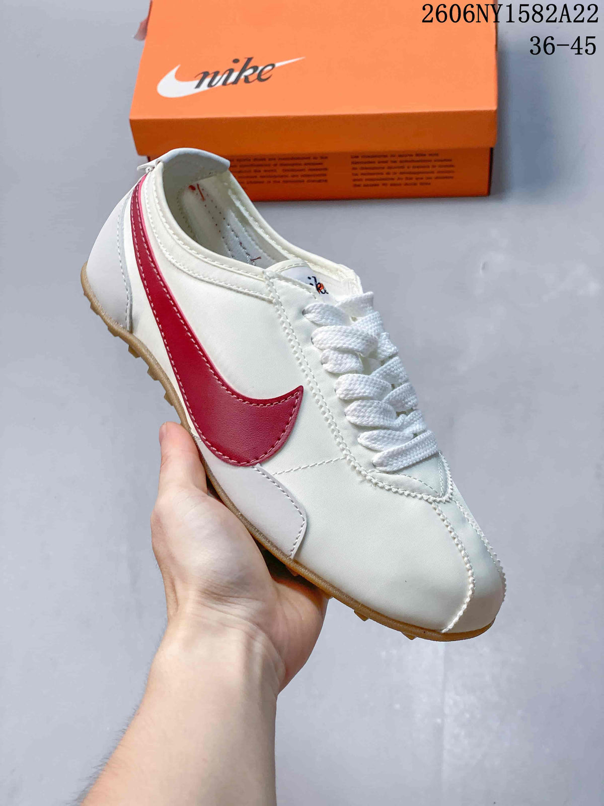Close view of a white Nike low-top sneaker with a red Swoosh and textured outsole