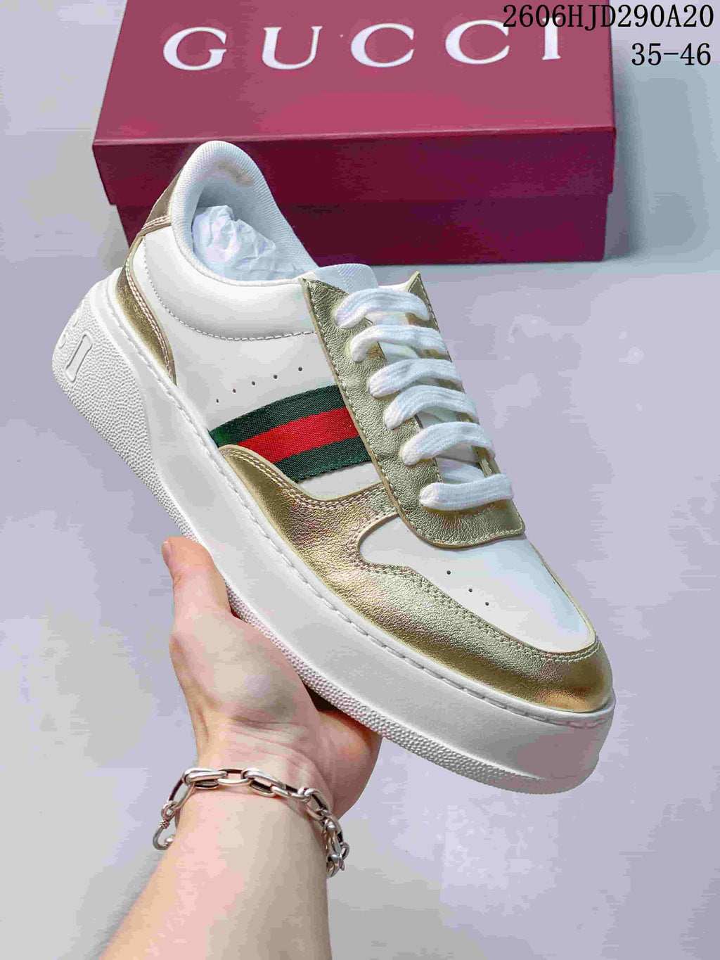 White low-top sneaker with metallic gold overlays and green-and-red side stripe