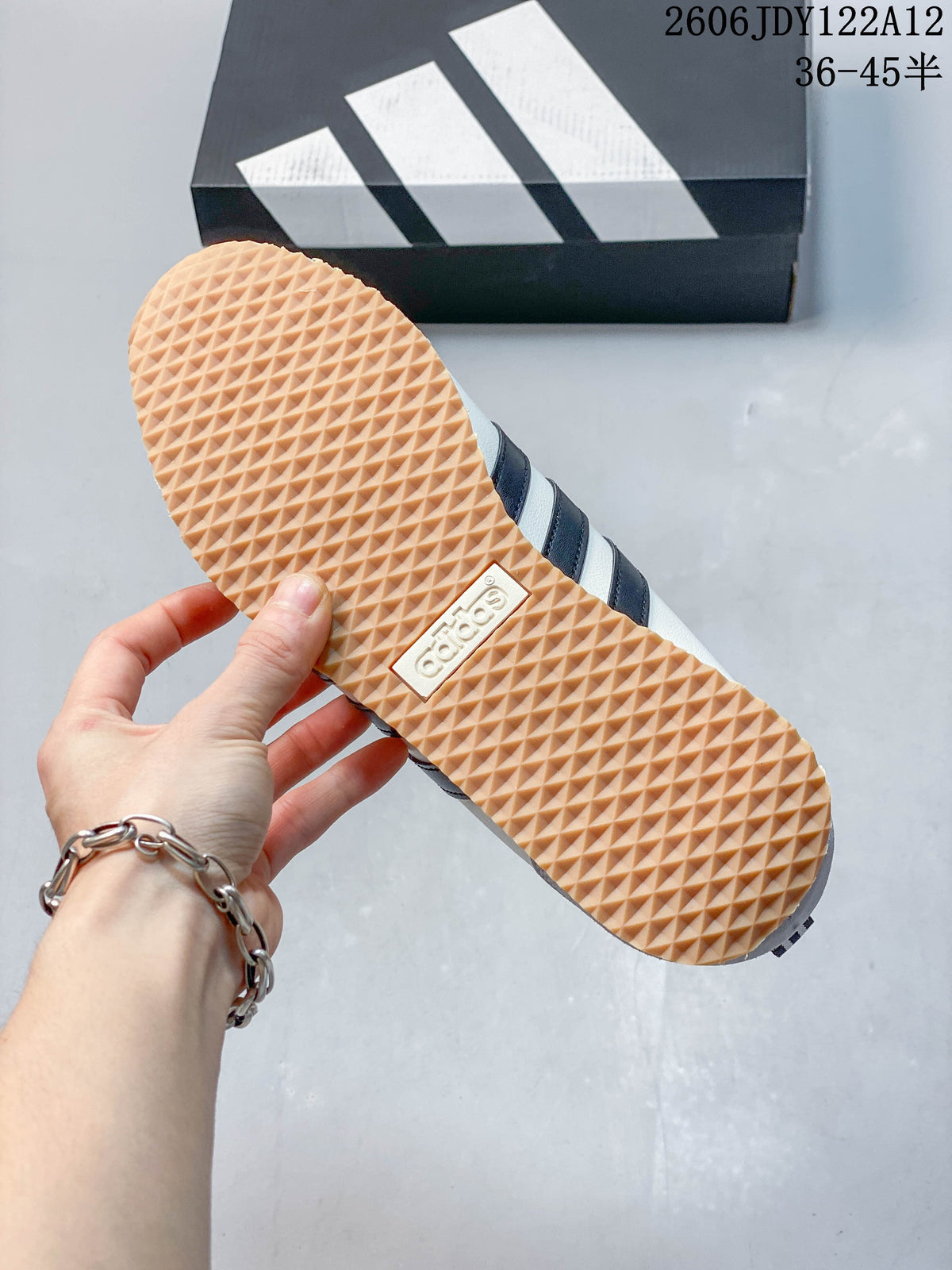 Textured gum-colored outsole of a white Adidas Originals VS Jog 2.0 sneaker.