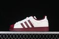 Side view of white adidas Superstar II sneakers with burgundy stripes, sole, and shell-style toe.