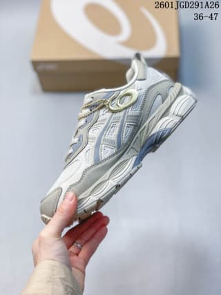 Side view of the light gray and white ASICS GEL-NYC RGD sneaker with layered panels, mesh sections, and a GEL-branded sole area.