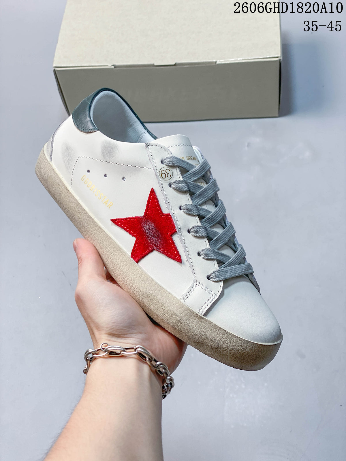 Angled side view of the white sneaker with a red star, gray laces, and dark green heel tab.
