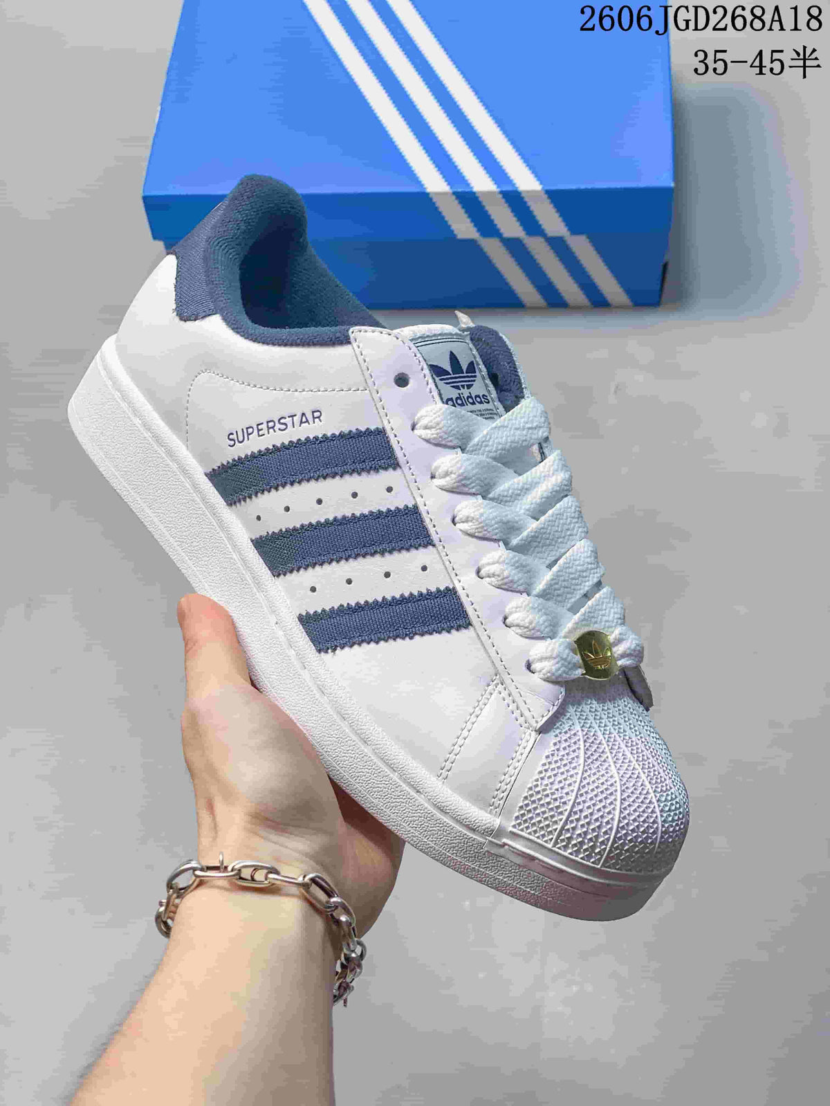 Angled view showing the white Adidas Superstar upper, navy stripes and shell toe.