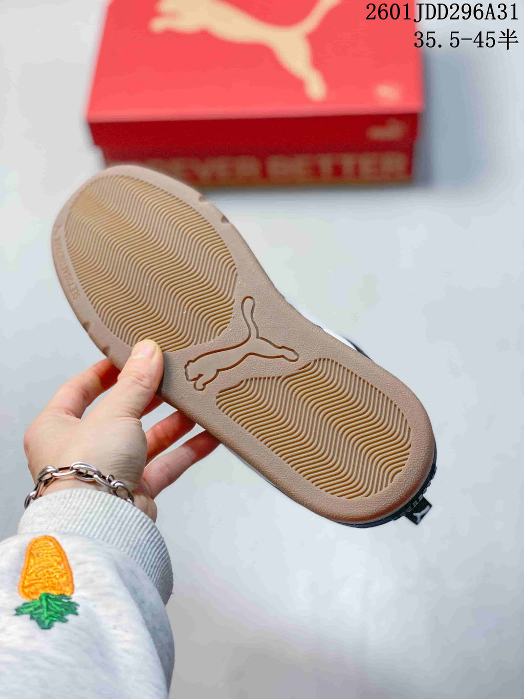 Gum-tone outsole of a dark sneaker with molded tread and a central cat-shaped logo