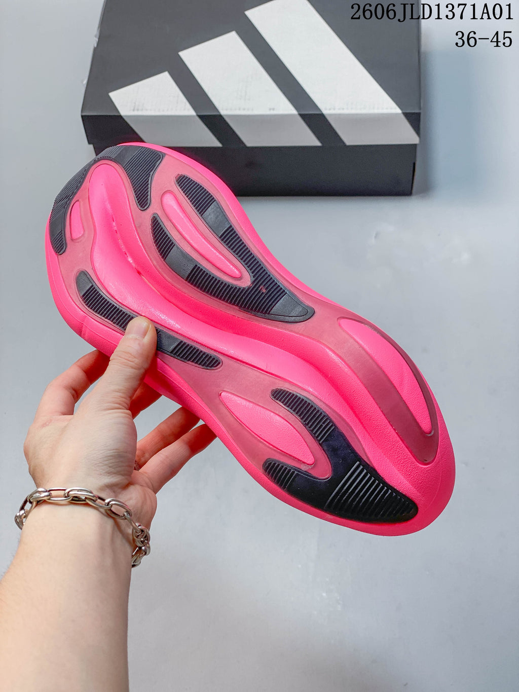 Underside of a pink Adidas Hyperboost sneaker showing dark traction sections.