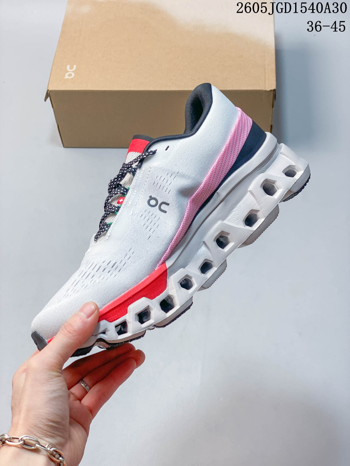 Side view of a white On Cloudmonster 2 shoe showing its sculpted sole and coral accents