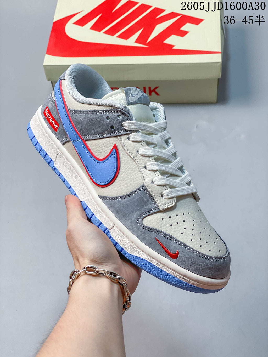 White and gray low-top sneaker with a blue Swoosh and red accents
