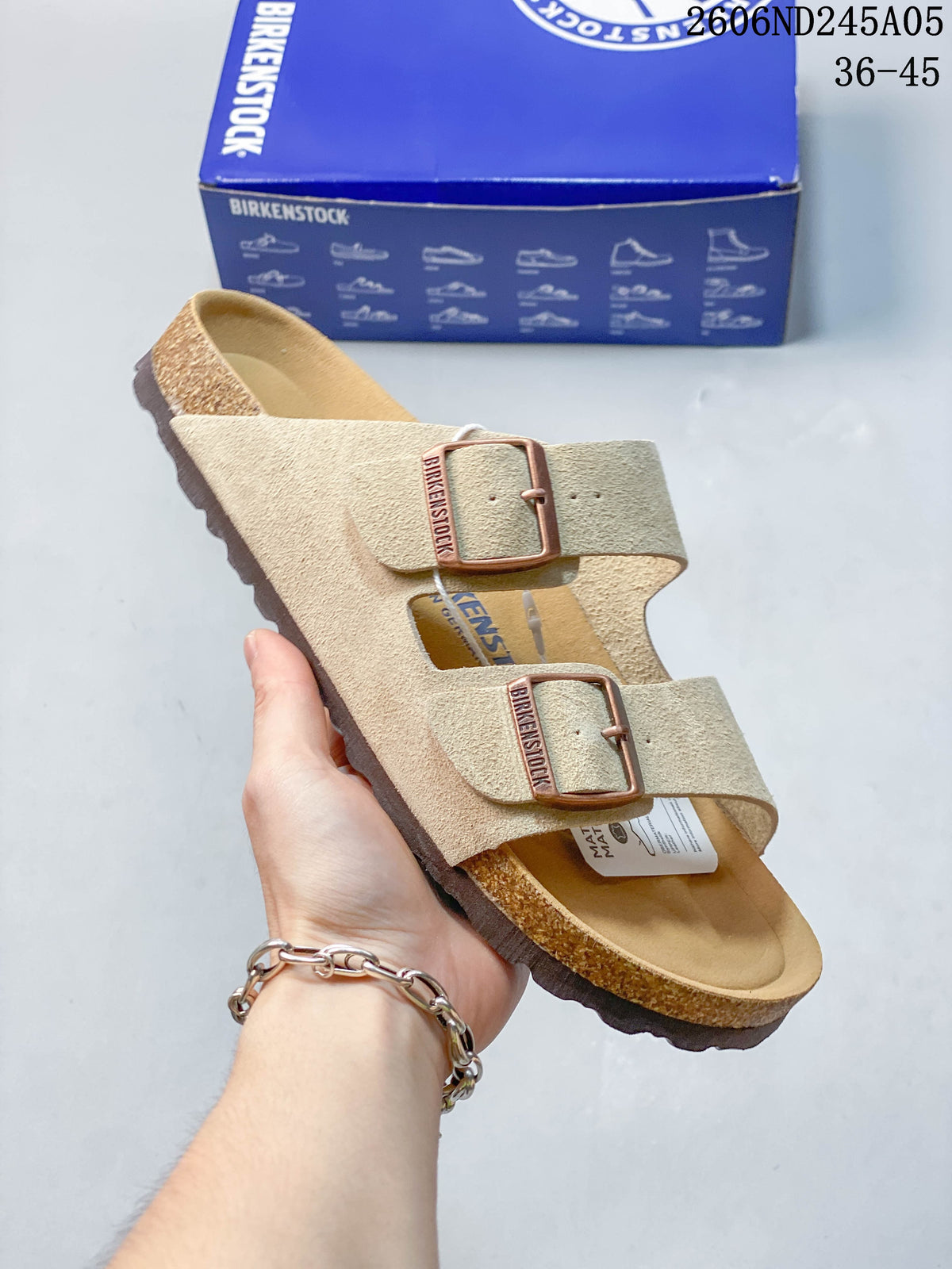 Angled view of the beige two-strap sandal with buckle details and footbed.