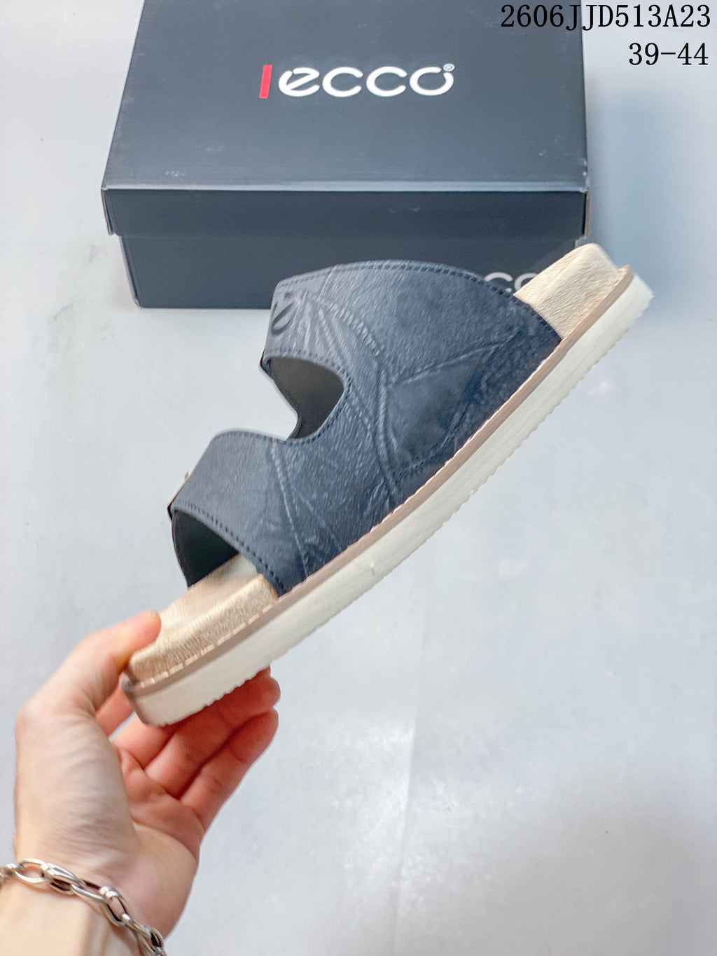 Side view of a slate-blue slide sandal with two open strap sections and a light-colored sole