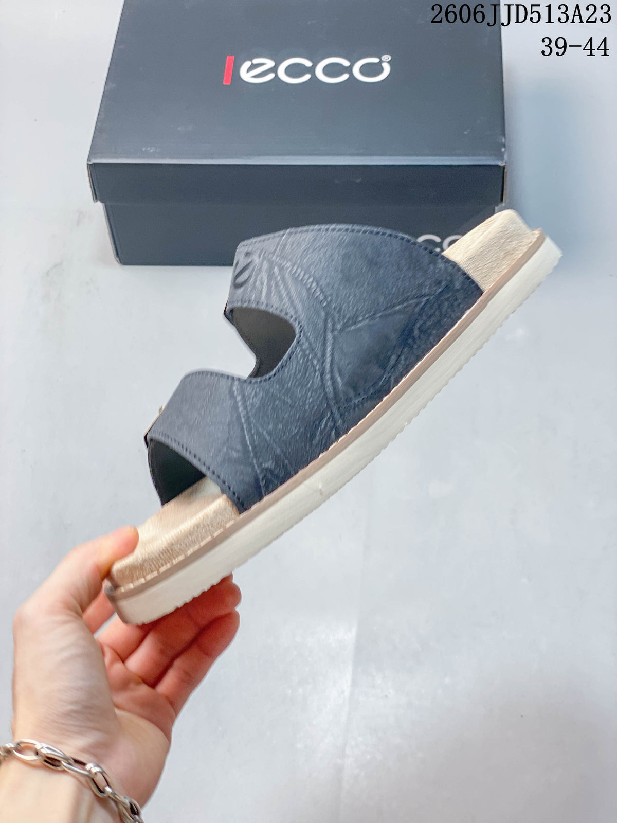 Side view of a slate-blue slide sandal with two open strap sections and a light-colored sole