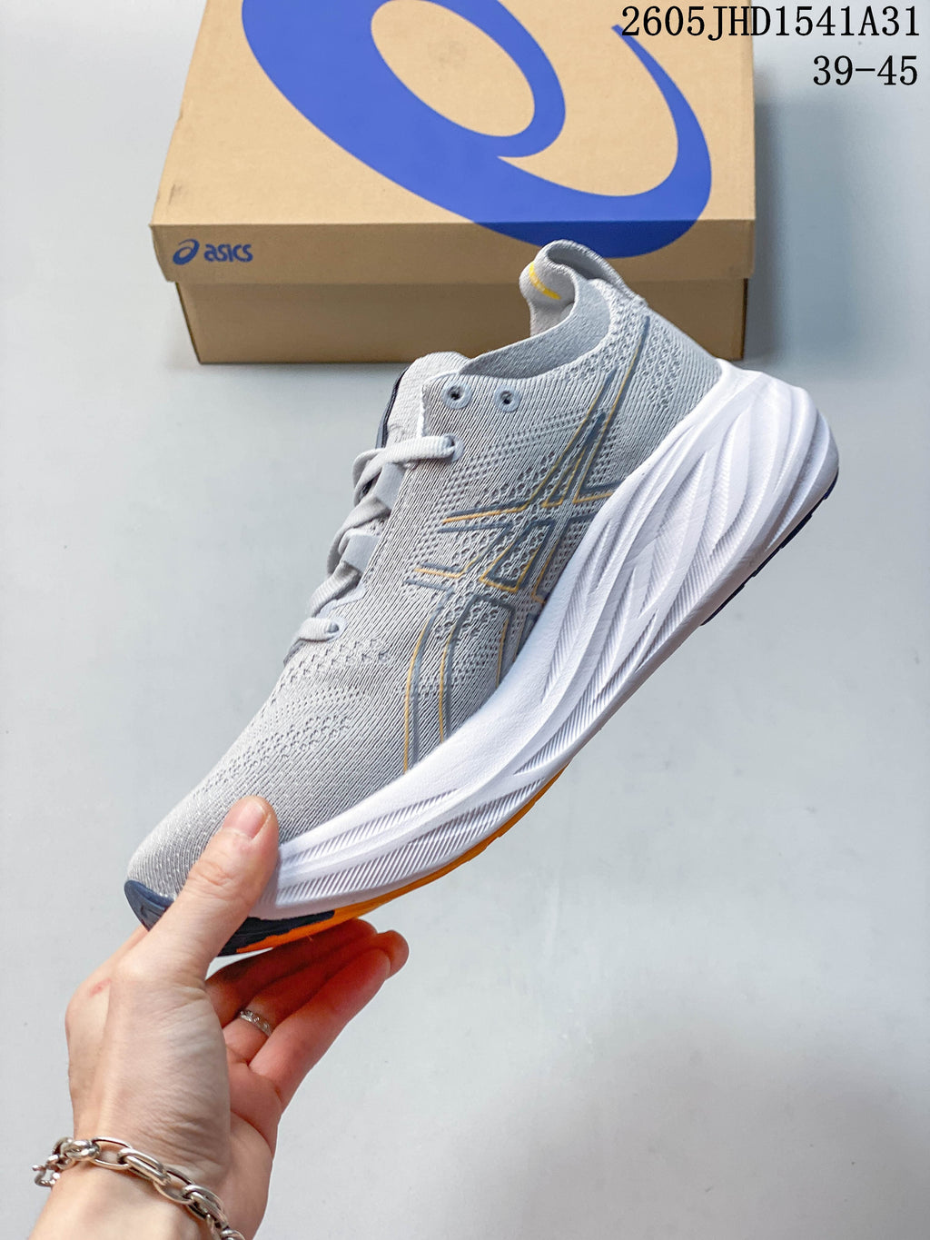 Side view of the gray ASICS running shoe with orange accents and a sculpted white midsole