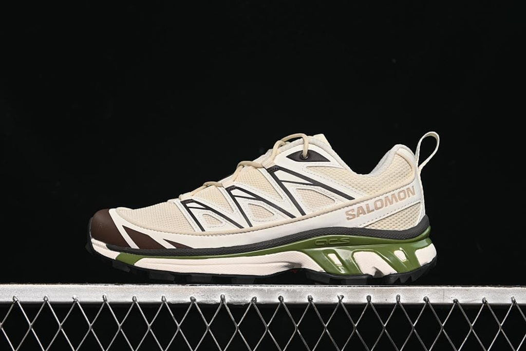 Side view of cream Salomon XT-6 Expanse sneakers with black details, dark brown toe accents, and a green midsole section.