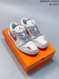 Pair of light-colored low-top sneakers with red accents and patterned laces on an orange box
