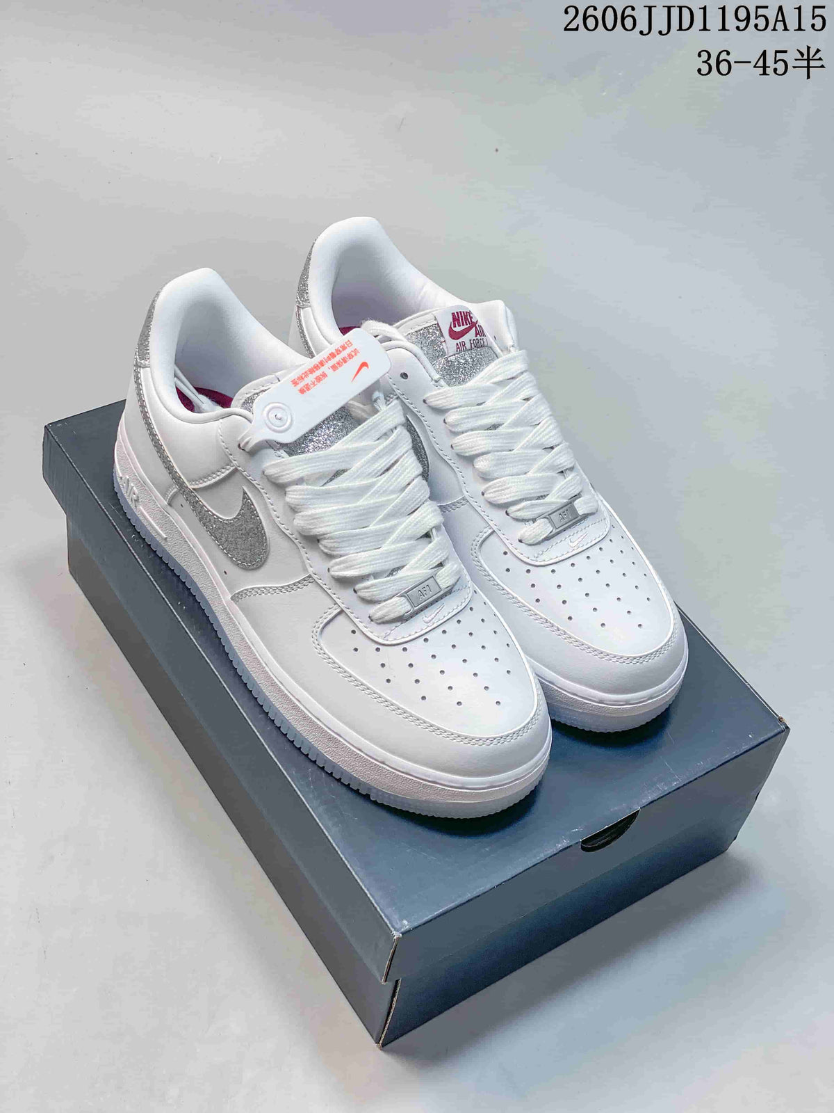 White low-top sneakers with silver reflective-look Swoosh accents, shown on a shoe box.